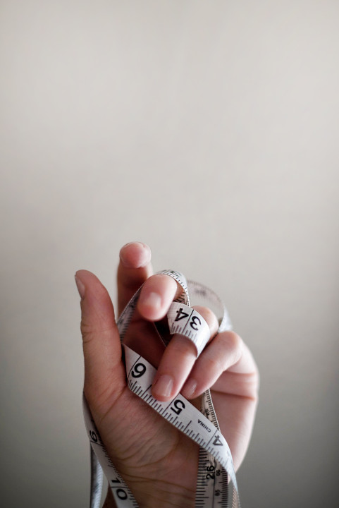 A hand wrapped in a tape measure